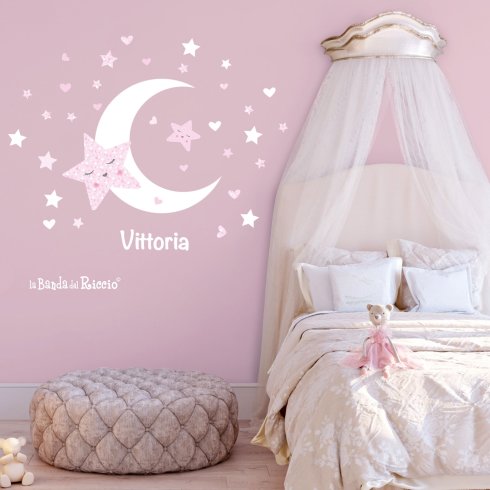 Adesivi murali bambini "Stelle e Luna": uno spicchio di luna circonado da tante stelle, colore bianco-rosa. Foto ambientata