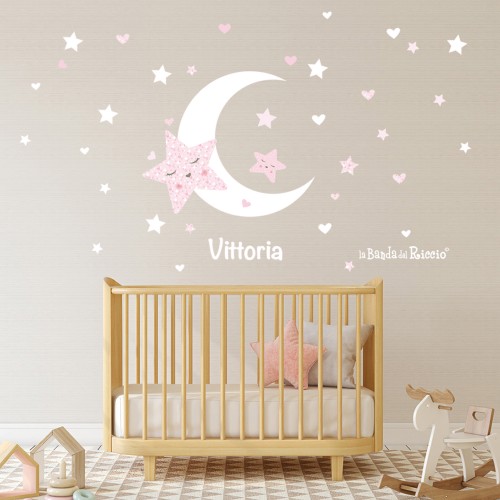 Adesivi murali bambini "Stelle e Luna": uno spicchio di luna circonado da tante stelle, colore bianco-rosa. Foto ambientata