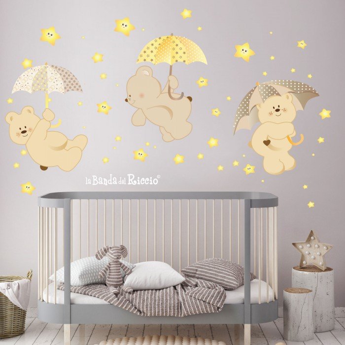 Three teddy bears with umbrellas and fluo stars. Photo beige