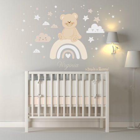 Teddy bear on the rainbow surrounded by stars and clouds. Beige color. Photo